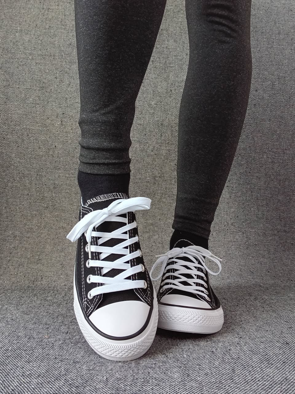 Baskets basses noir et blanc femme style Converse bicolore portées avec un legging gris anthracite