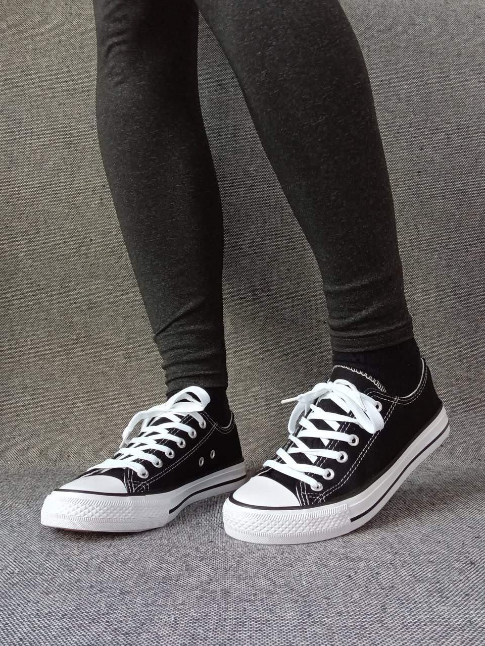 Baskets basses noir et blanc femme style Converse bicolore avec lacets blancs, portées avec un legging gris