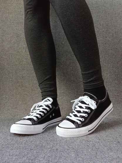 Baskets basses noir et blanc femme style Converse bicolore avec lacets blancs, portées avec un legging gris