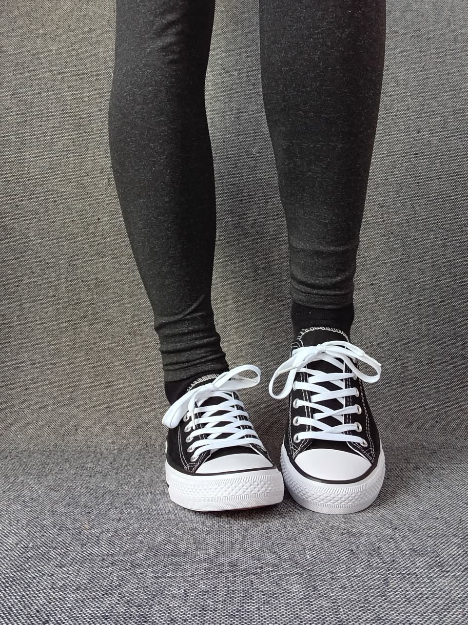 Baskets basses noir et blanc femme style Converse bicolore portées avec un legging gris anthracite
