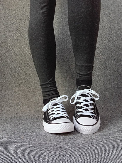 Baskets basses noir et blanc femme style Converse bicolore portées avec un legging gris anthracite