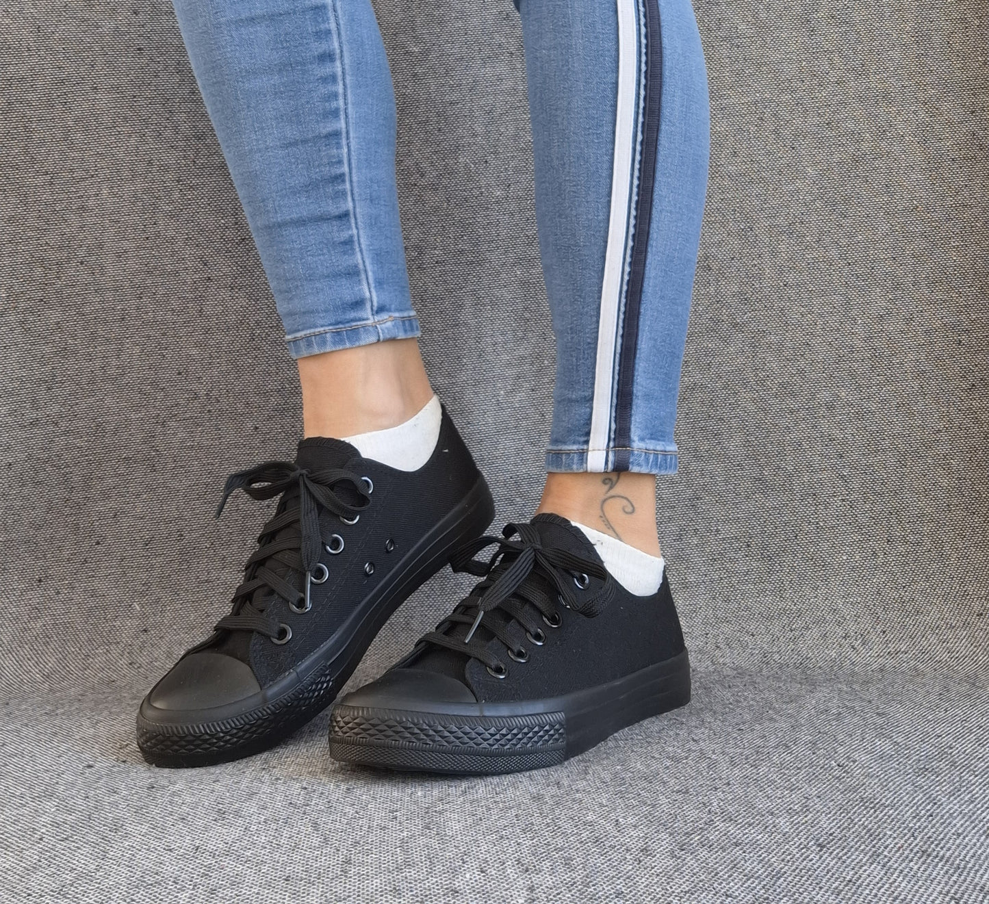 Baskets basses noir femme style Converse classique portées avec un jean slim à bandes latérales