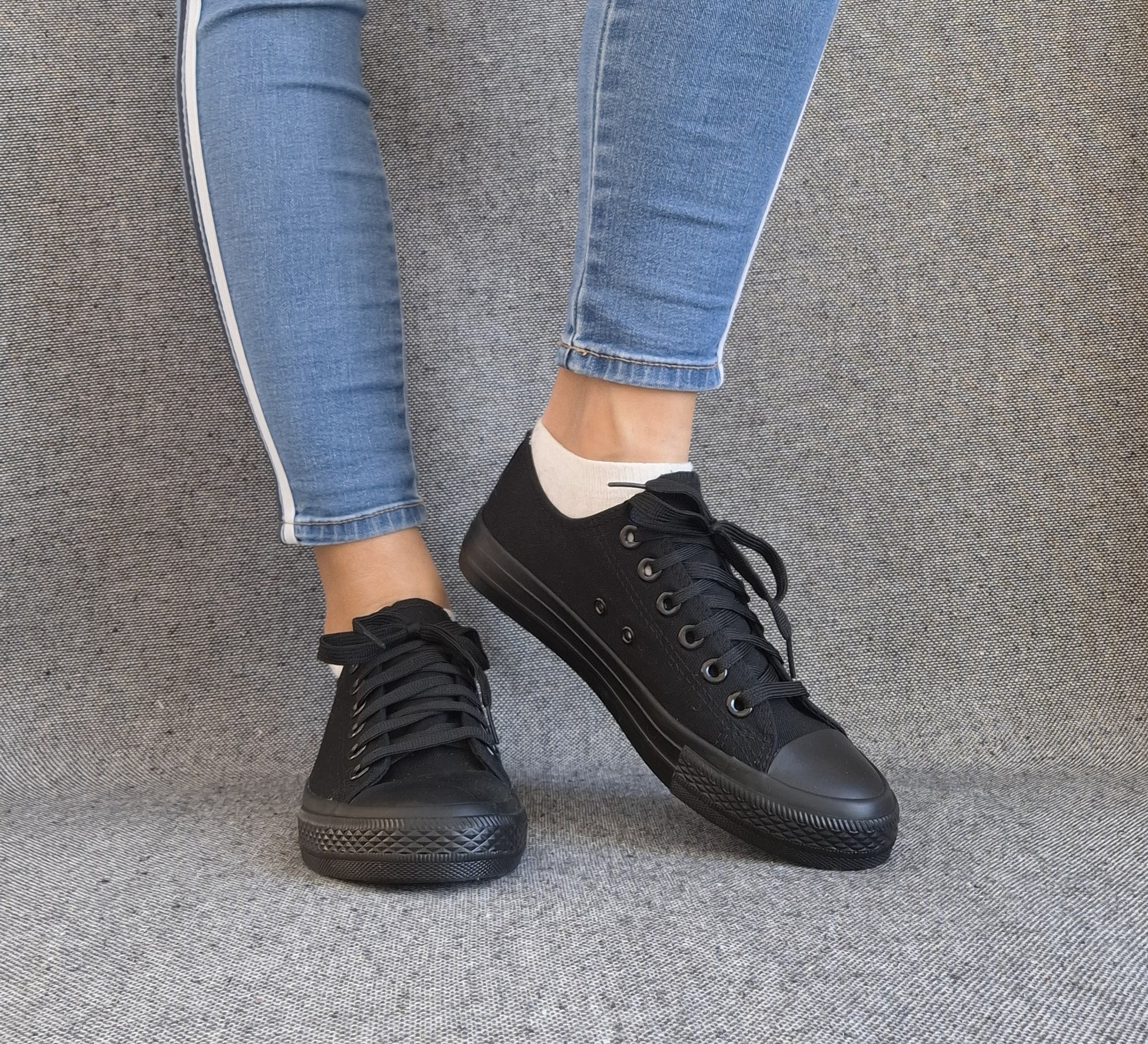 Baskets basses noir femme style Converse classique portées avec un jean slim bleu, vue de face