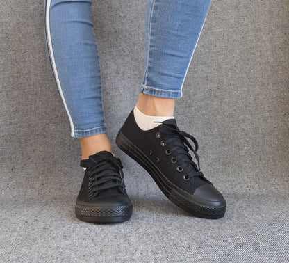 Baskets basses noir femme style Converse classique portées avec un jean slim bleu, vue de face