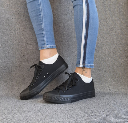 Baskets basses noir femme style Converse classique portées avec un jean skinny bleu à bandes latérales