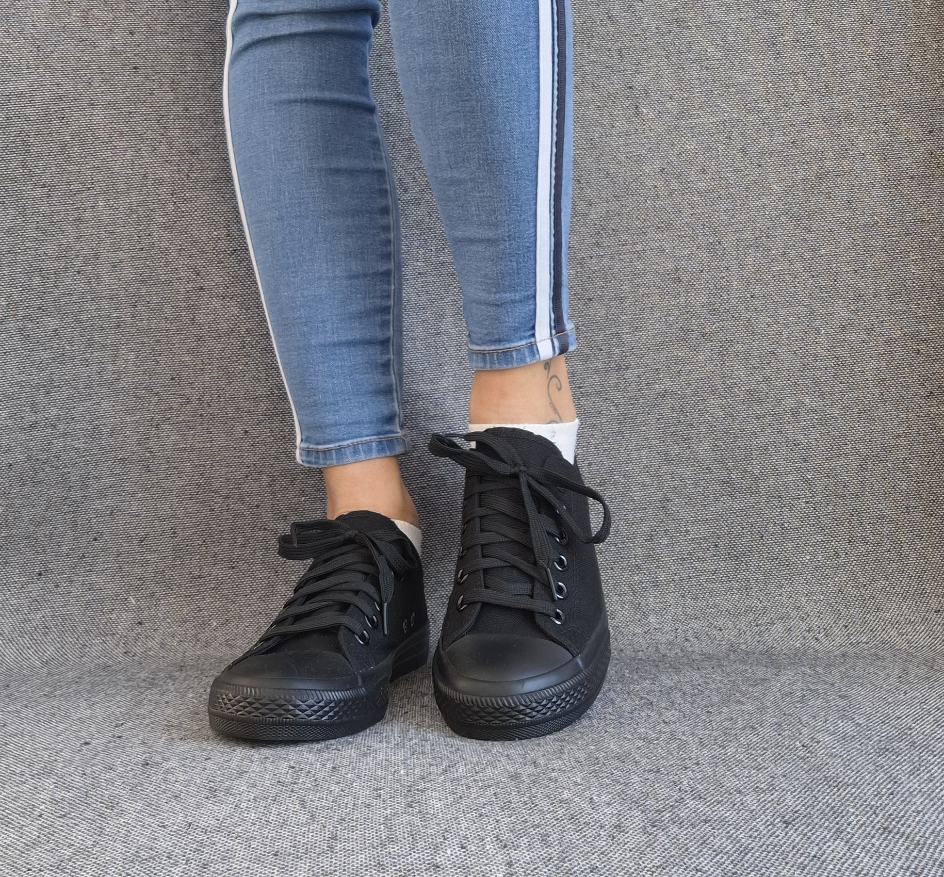 Baskets basses noir femme style Converse classique portées avec un jean slim à bandes blanches