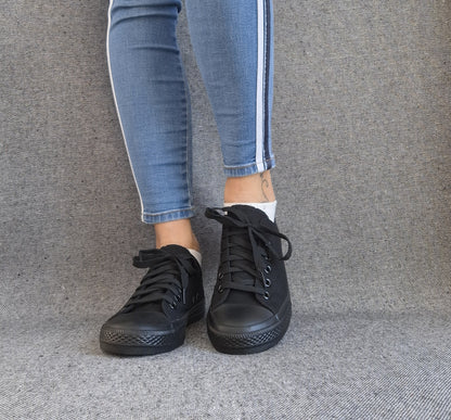 Baskets basses noir femme style Converse classique portées avec un jean slim à bandes blanches