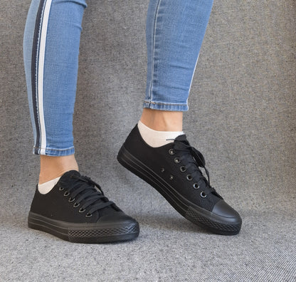Baskets basses noir femme style Converse classique portées avec un jean slim bleu à bande blanche