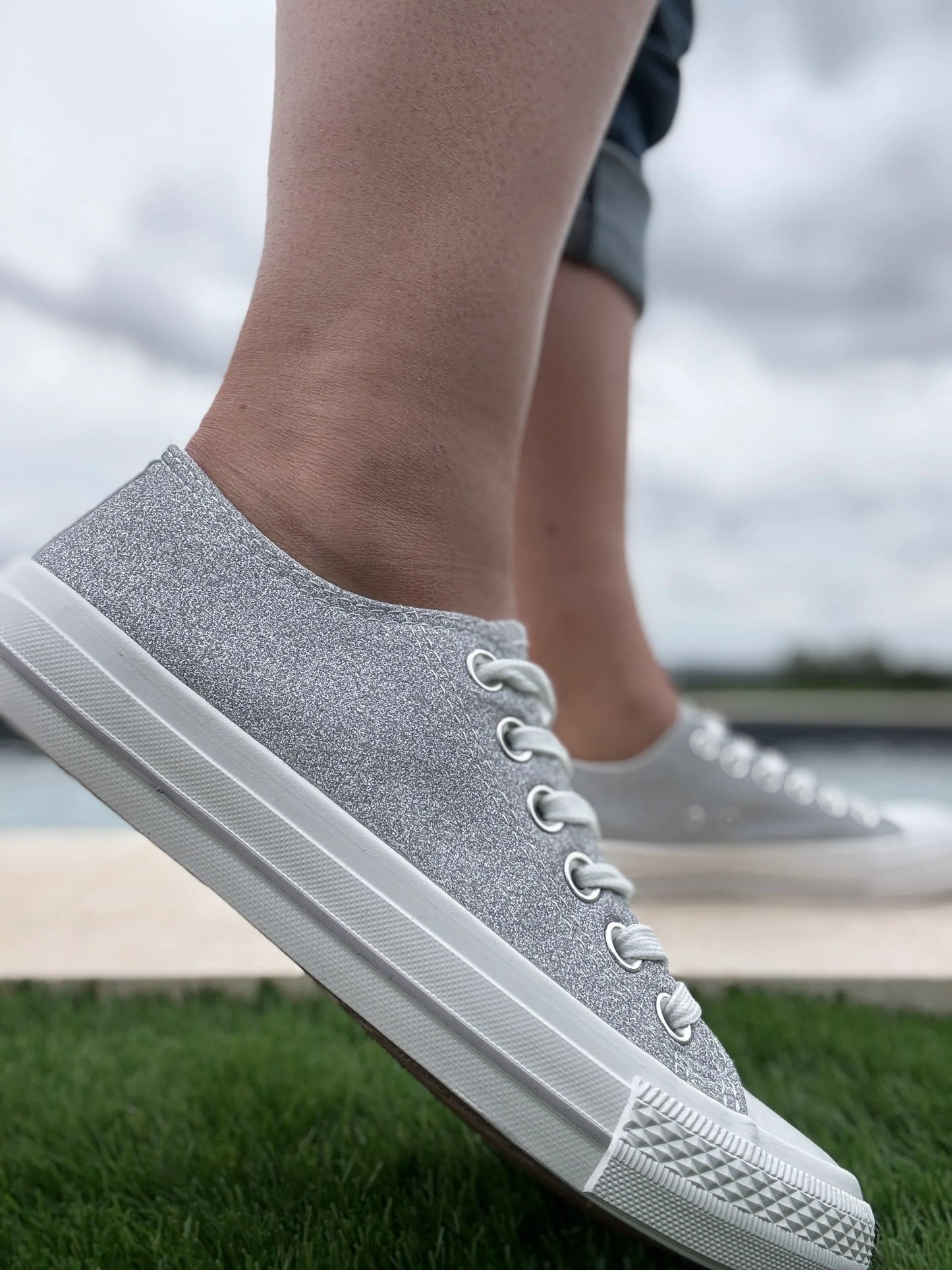 Baskets basses pailletées argentées femme style Converse portées sur herbe, tige glitter silver et semelle blanche