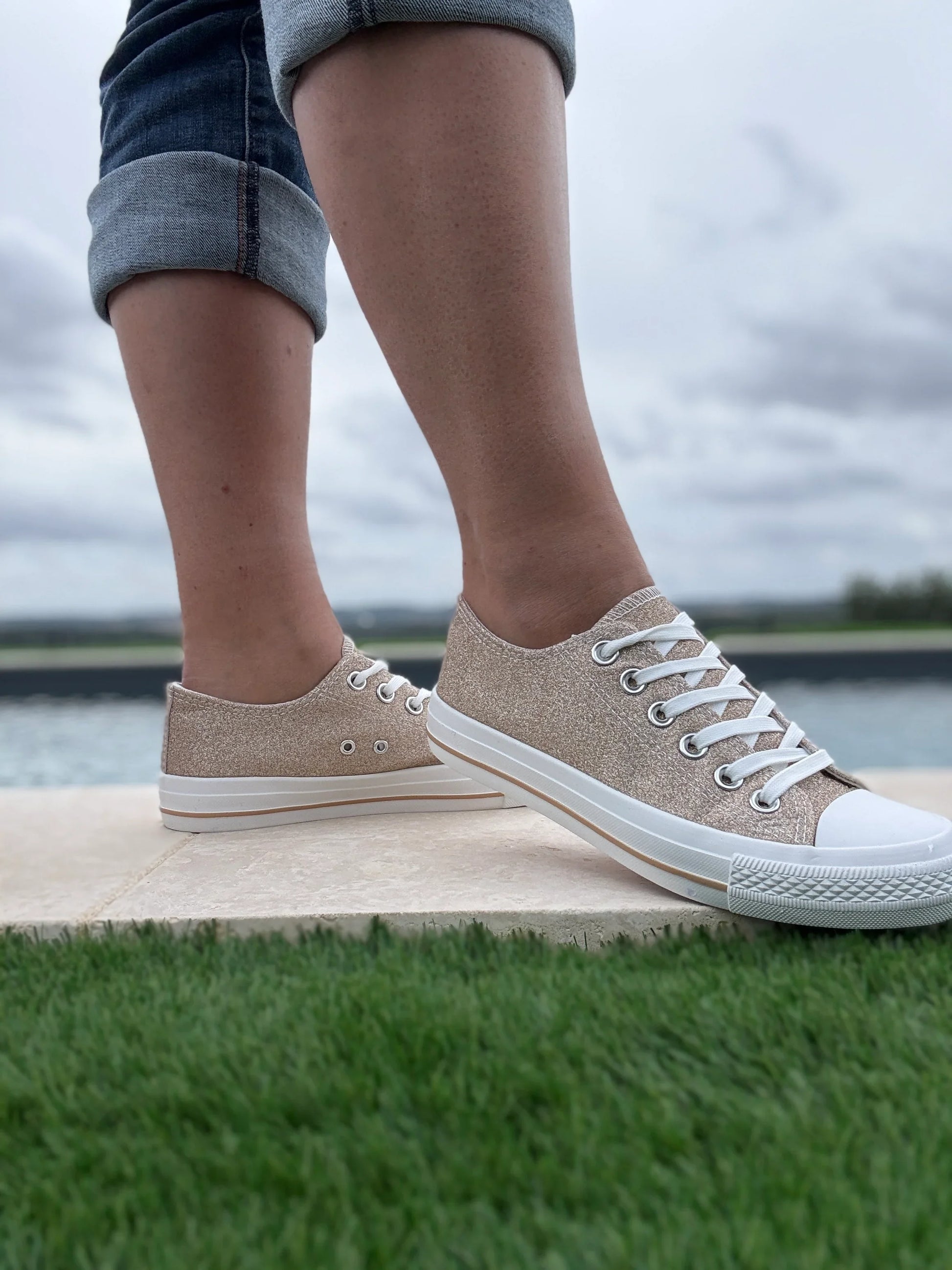 Baskets basses pailletées dorées femme style Converse avec lacets blancs, portées avec un jean court