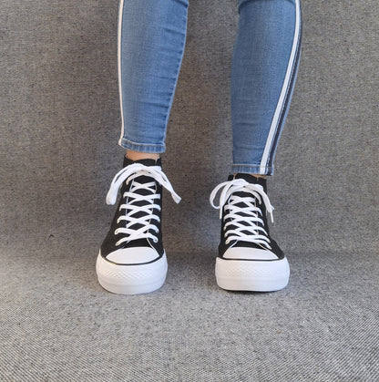 Baskets hautes montantes femme noires style Converse à lacets blancs, portées avec un jean slim bleu