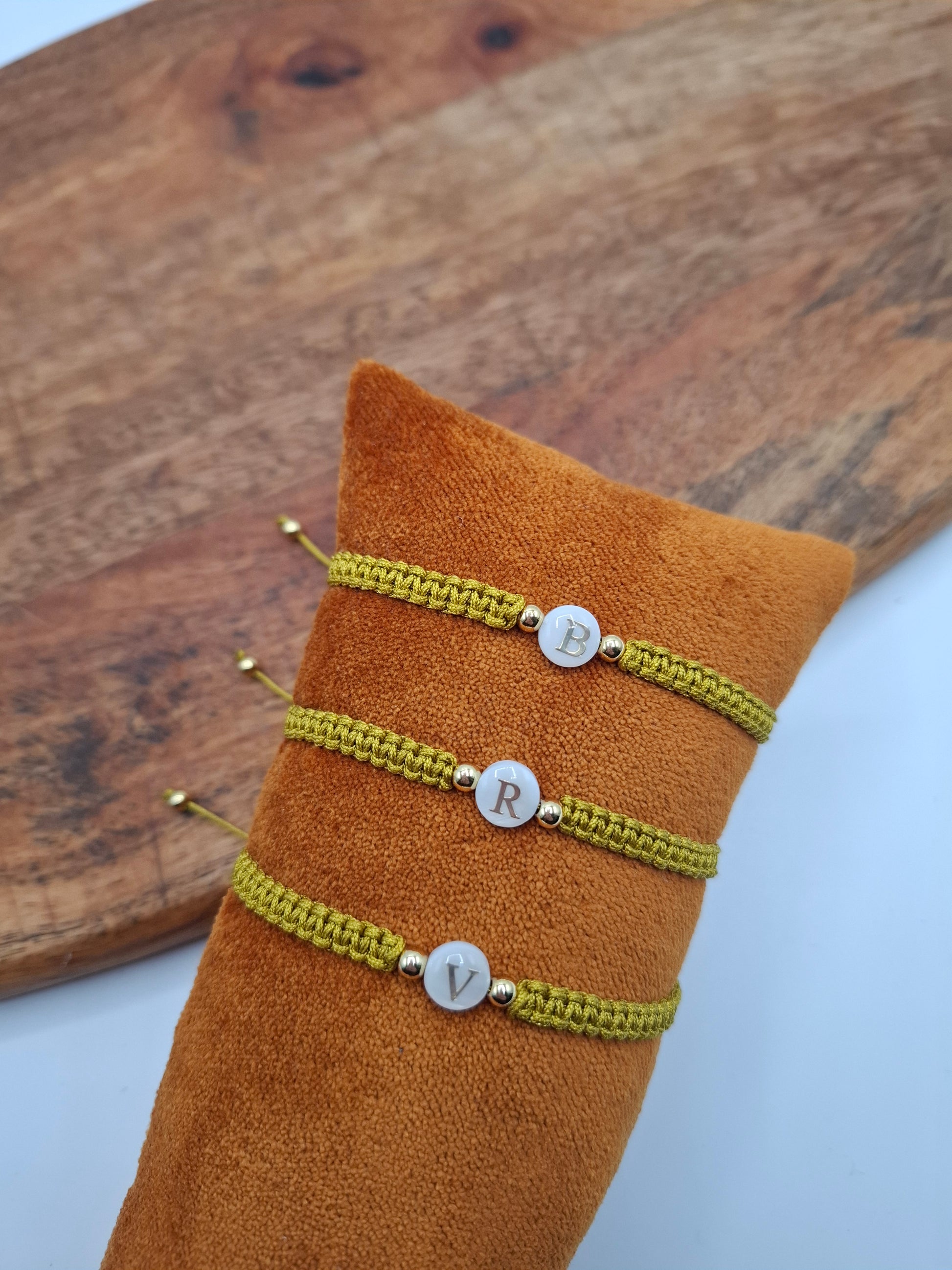 Yellow braided initial bracelets with gold accents on display at Le Petit Placard.