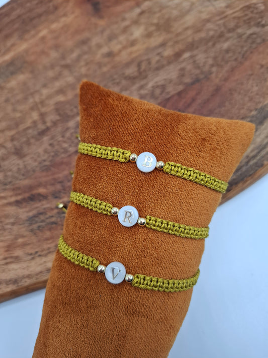 Green braided bracelets with gold letter charms B, R, V on display at Le Petit Placard