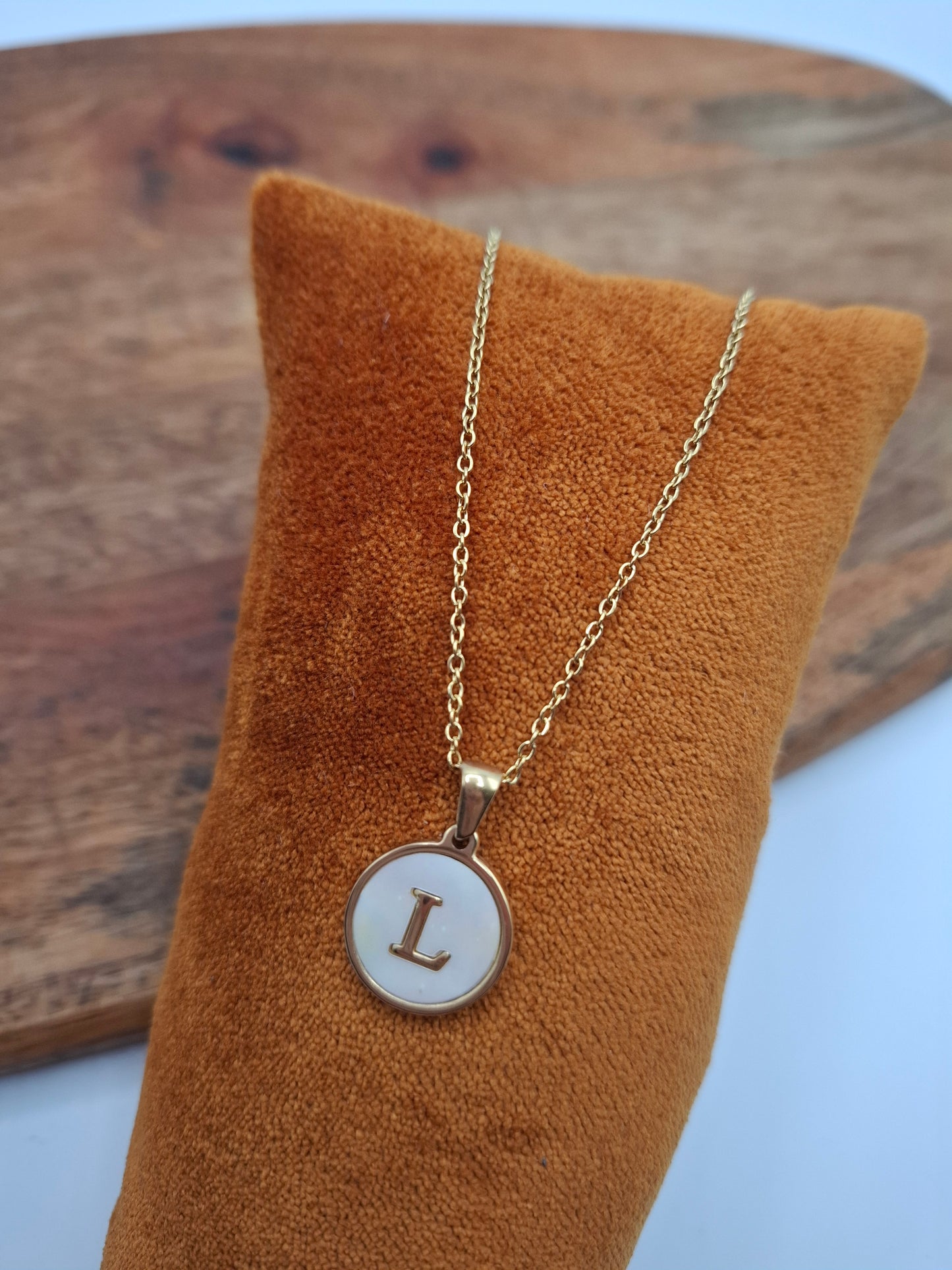 Gold necklace with round L initial pendant displayed on brown velvet, Le Petit Placard accessory