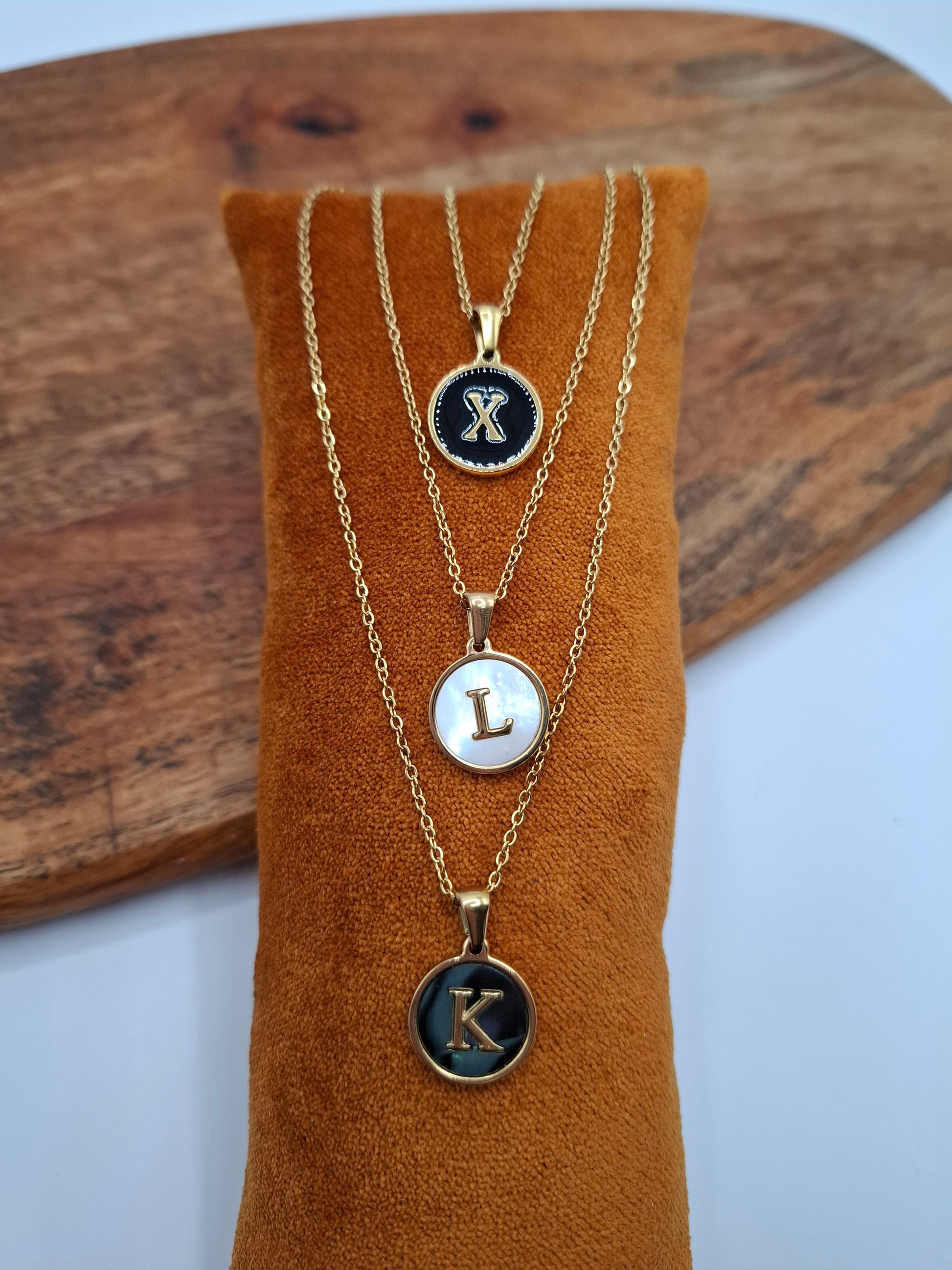 Gold initial necklaces X, L, K on brown display, Le Petit Placard jewelry accessory