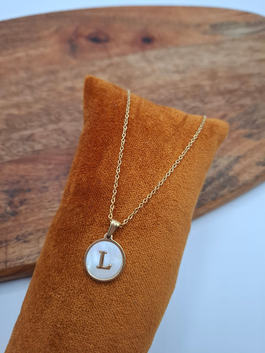 Gold necklace with mother-of-pearl 'L' pendant on orange velvet display, Le Petit Placard