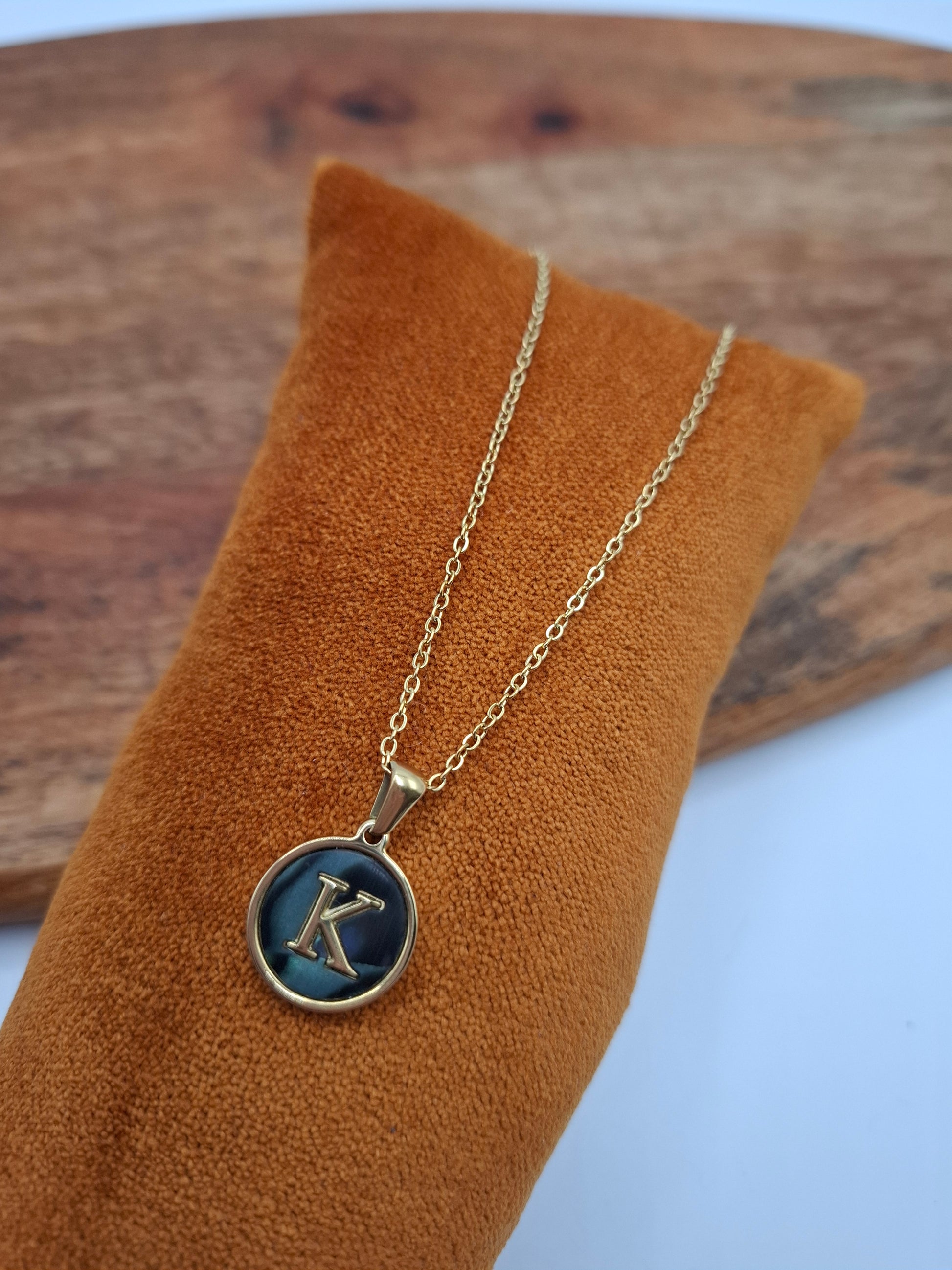 Gold necklace with blue letter K pendant on orange velvet display, Le Petit Placard jewelry