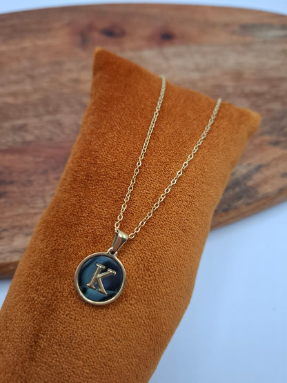 Gold necklace with blue letter K pendant on orange velvet display, Le Petit Placard jewelry