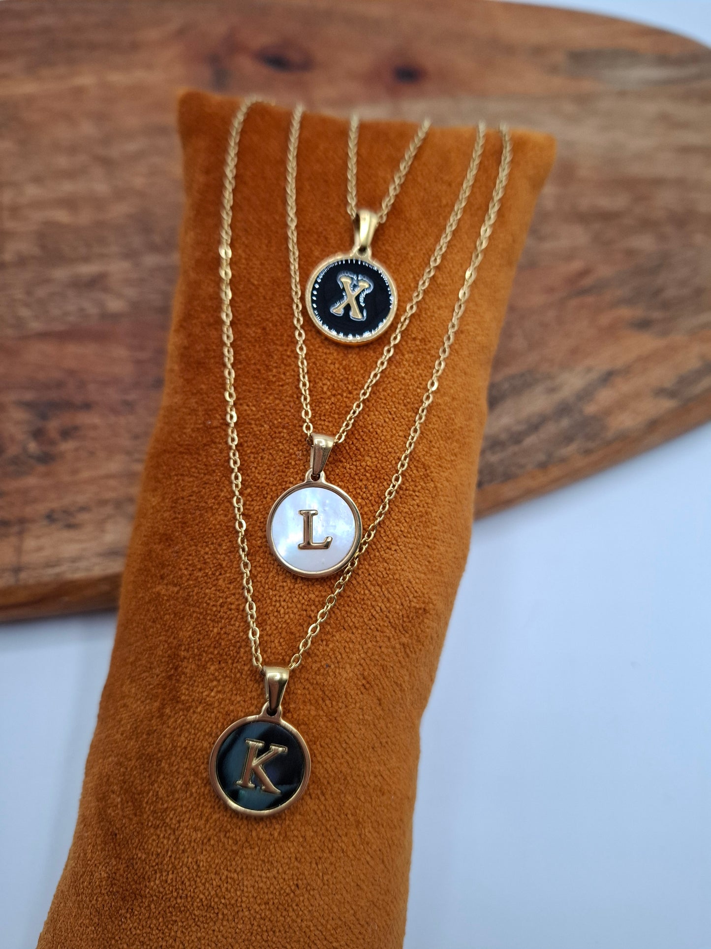 Gold initial pendant necklaces X, L, K on display at Le Petit Placard accessories shop