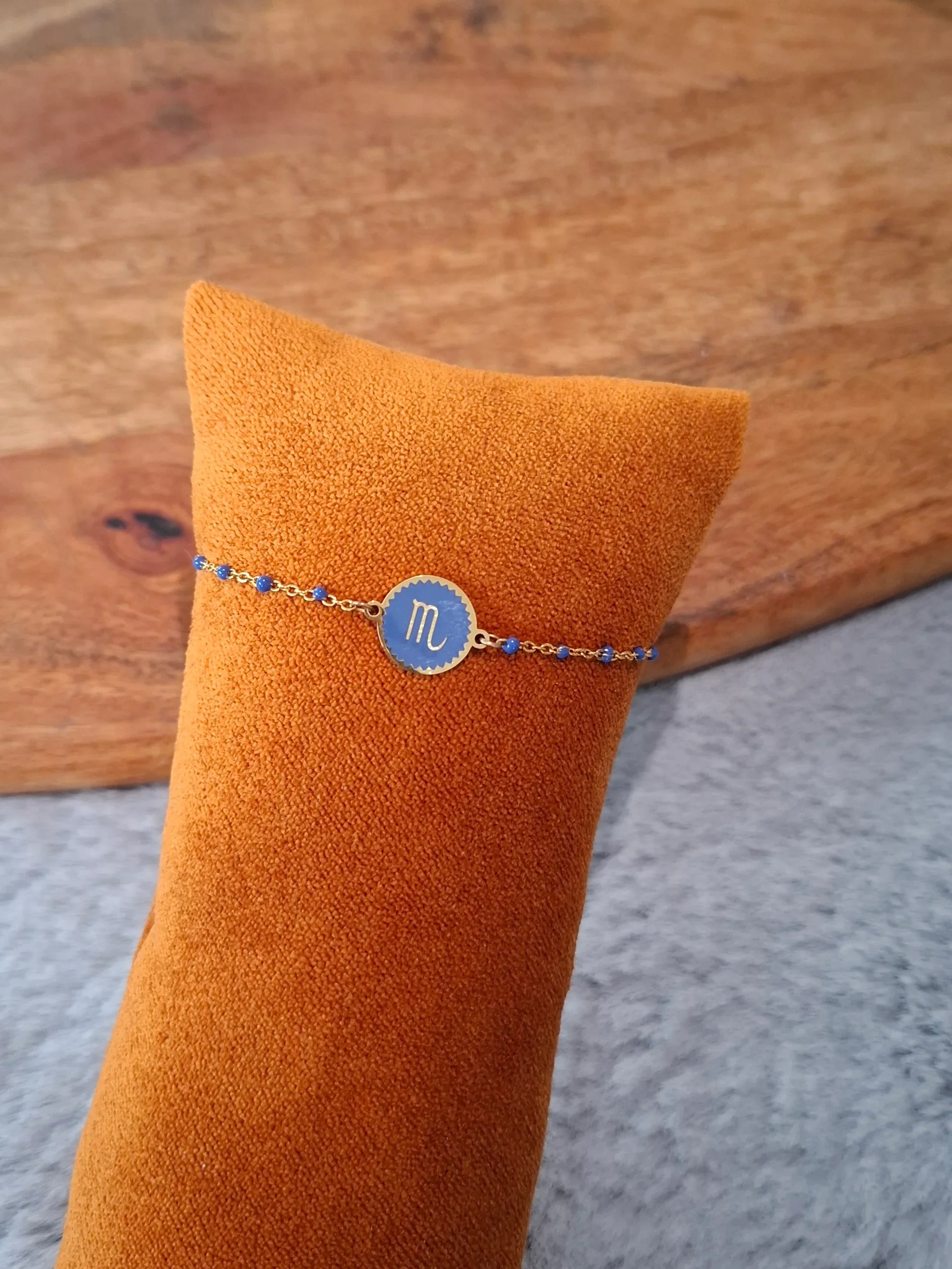 Bracelet chaîne fine dorée signe astrologique Scorpion, médaillon bleu zodiacal sur présentoir orange