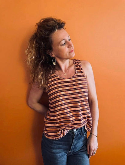 Femme portant un débardeur à rayures brun et jaune upcyclé en coton lin, associé à un jean, fond orange
