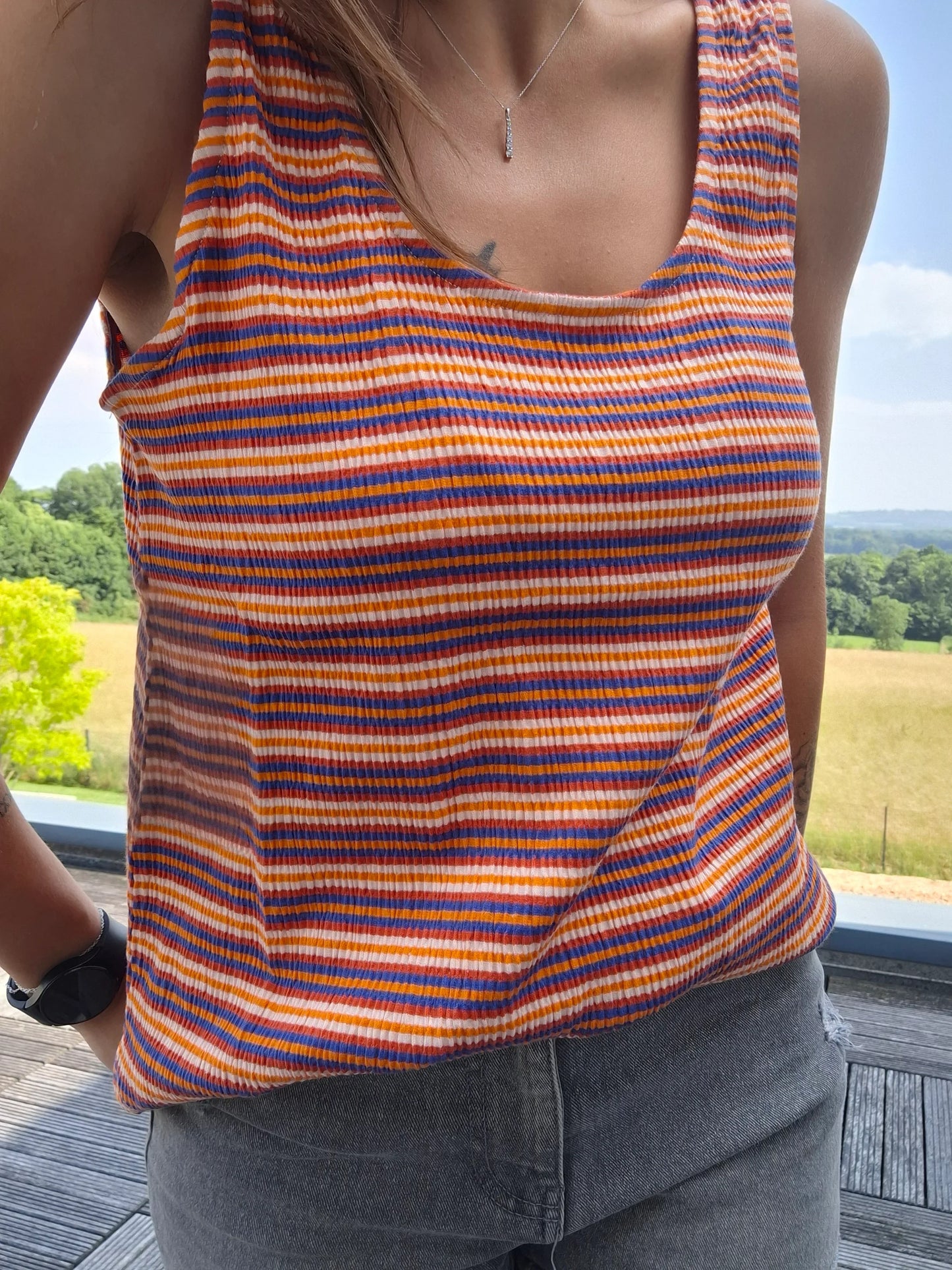 Débardeur à rayures upcyclé en coton/lin porté par une femme, motif multicolore orange, bleu et blanc