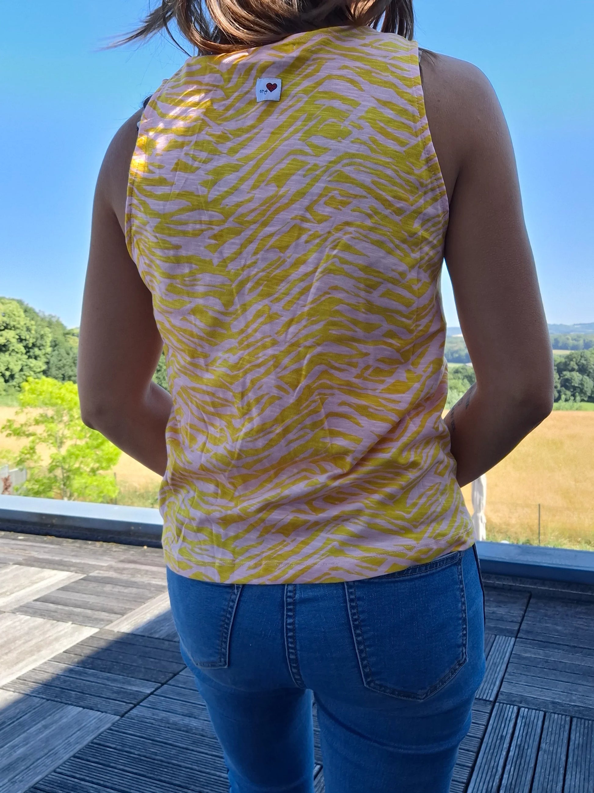 Débardeur upcyclé bariolé jaune à motif zébré en coton/lin, porté de dos avec un jean, en extérieur