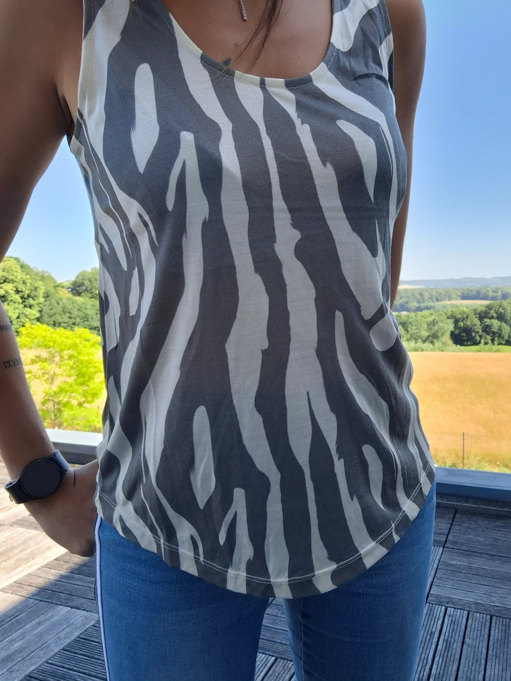 Débardeur upcyclé motif zèbre gris et blanc en coton/lin porté par une femme, fond de campagne ensoleillée