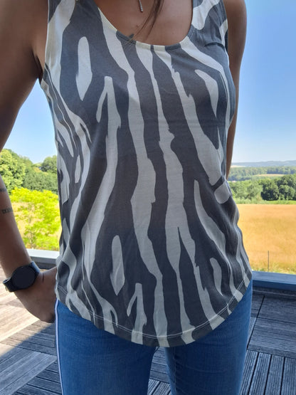 Débardeur upcyclé motif zèbre gris et blanc en coton/lin porté par une femme, fond de campagne ensoleillée