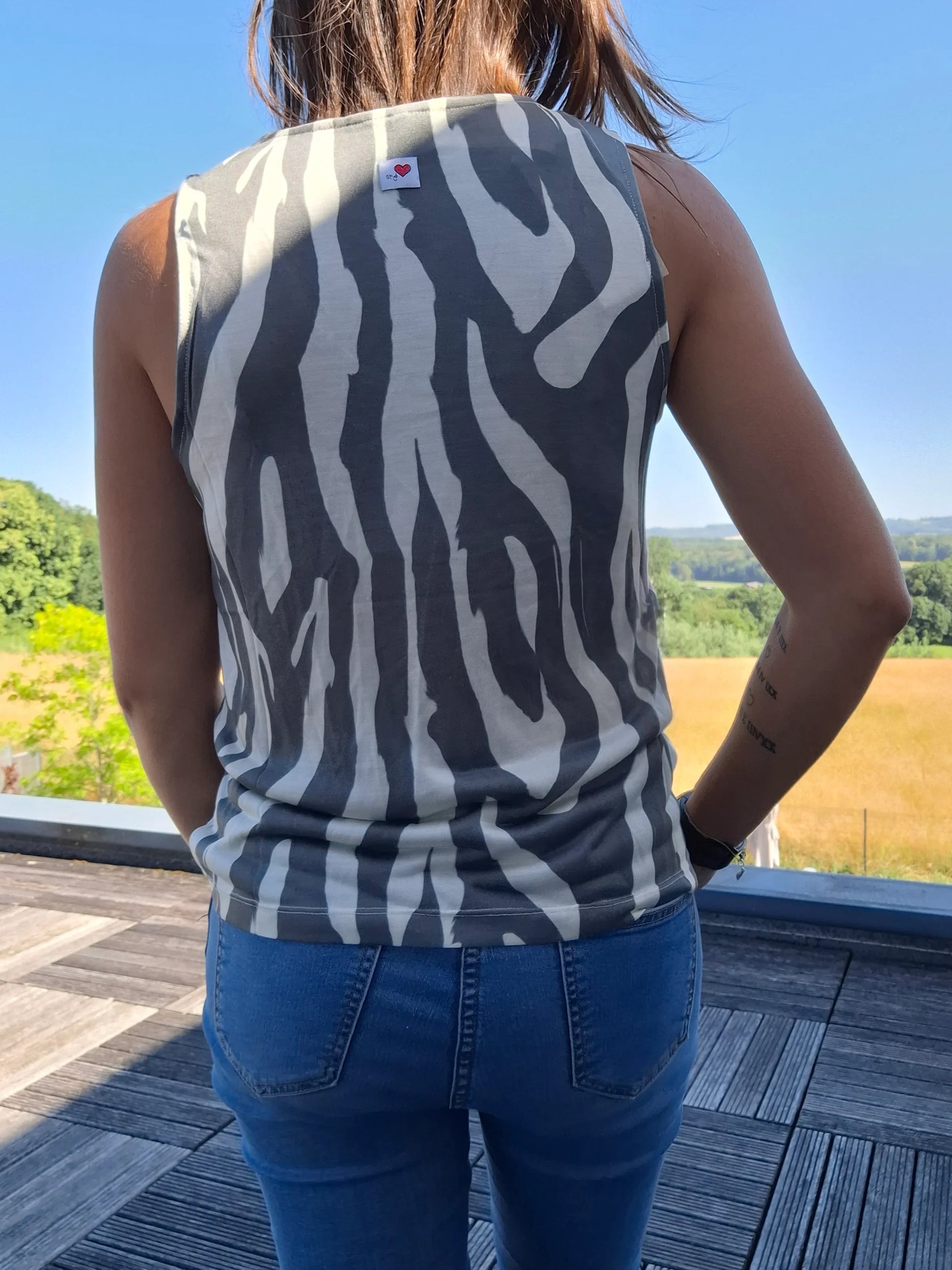 Débardeur motif zèbre upcyclé coton/lin gris et blanc porté de dos avec un jean, vue extérieure ensoleillée