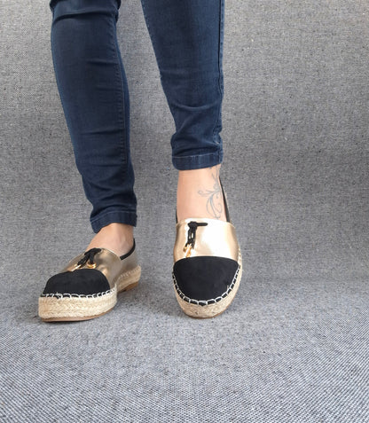 Espadrilles plates bicolore or et noir portées avec un jean, semelle tressée en jute et bout noir suédé