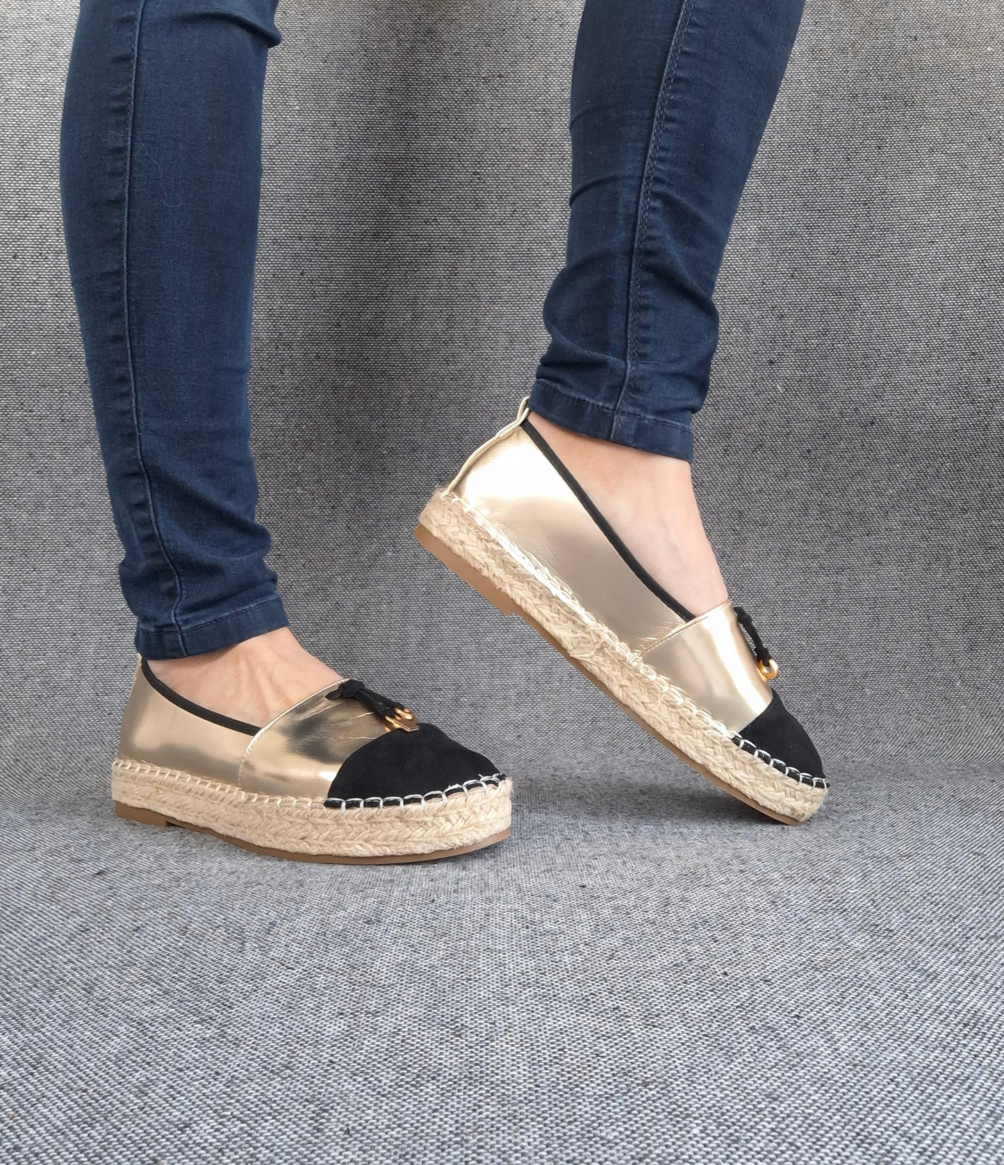 Espadrilles plates bicolore or et noir à semelle tressée portées avec un jean slim bleu