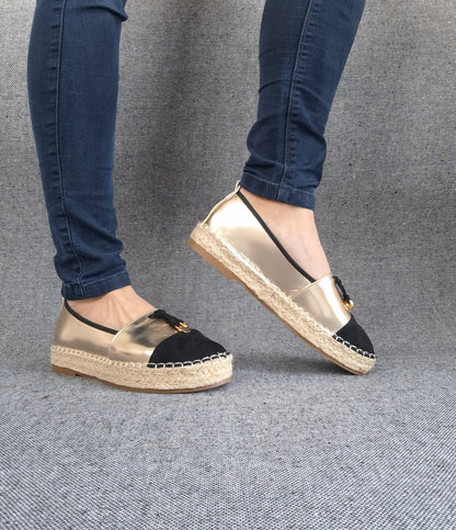 Espadrilles plates bicolore or et noir à semelle tressée portées avec un jean slim bleu