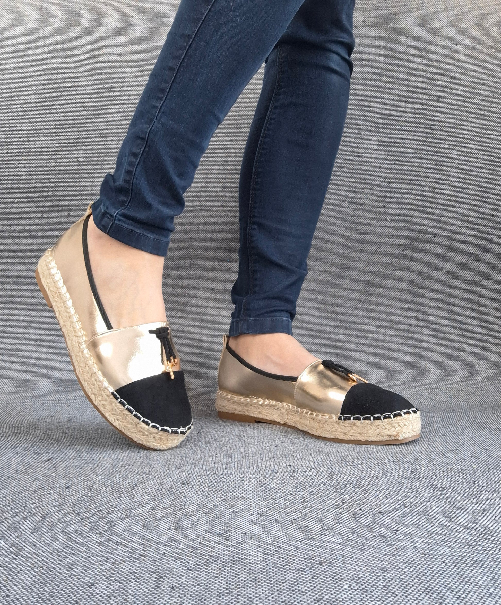 Espadrilles plates bicolore or et noir portées avec un jean, semelle tressée en jute, bout noir et tige dorée