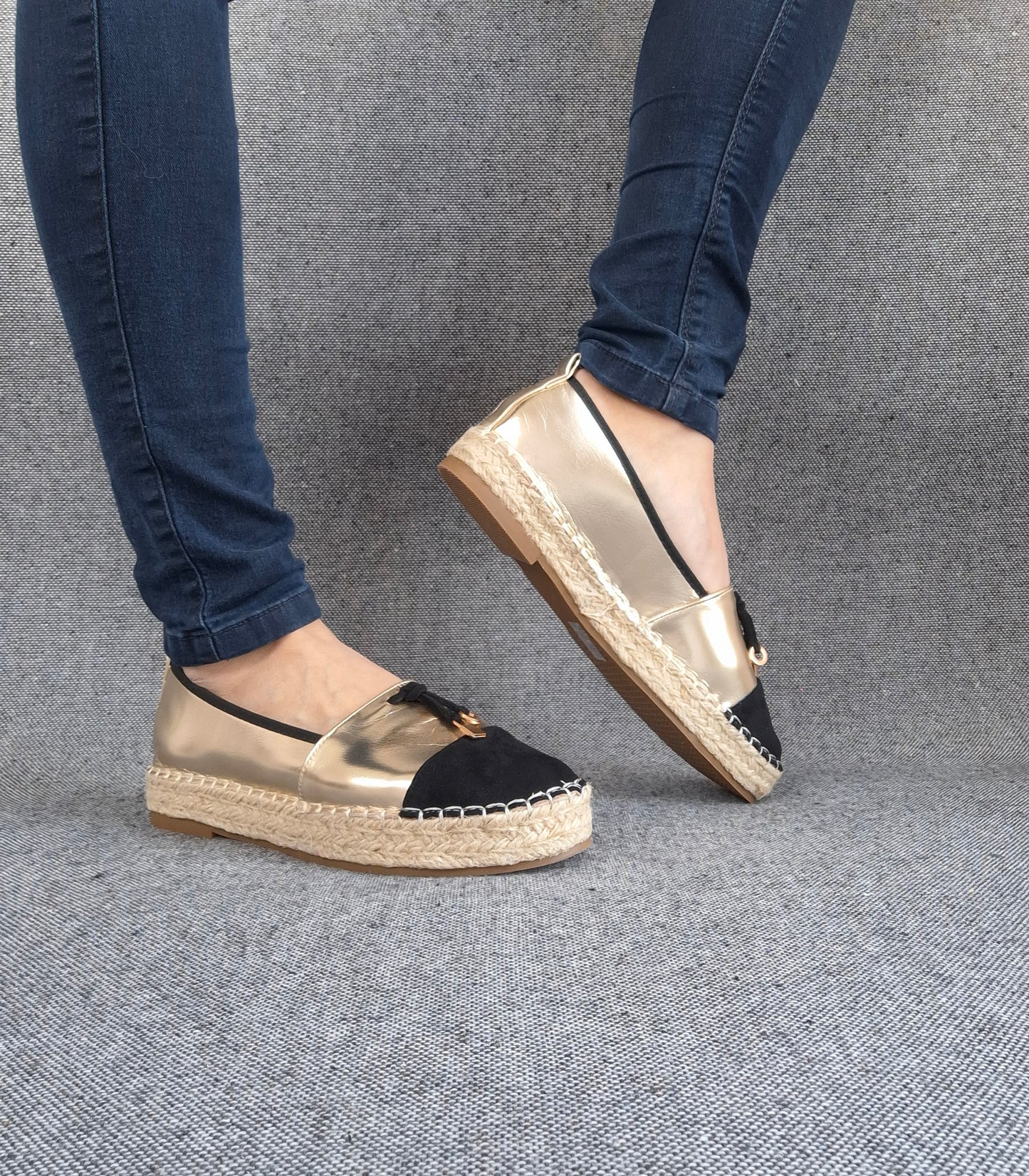 Espadrilles plates bicolore or et noir portées avec un jean, semelle tressée en jute et bout noir contrasté