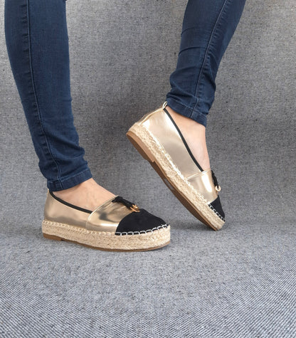 Espadrilles plates bicolore or et noir portées avec un jean, semelle tressée en jute et bout noir contrasté