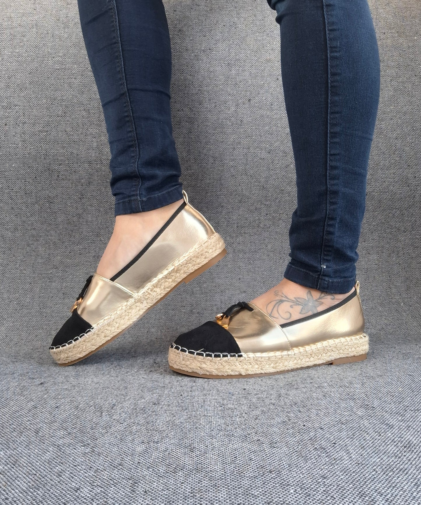 Espadrilles plates bicolore or et noir à semelle tressée portées avec un jean slim bleu