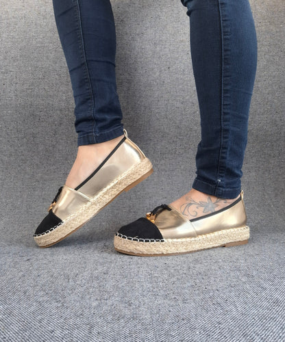 Espadrilles plates bicolore or et noir à semelle tressée portées avec un jean slim bleu