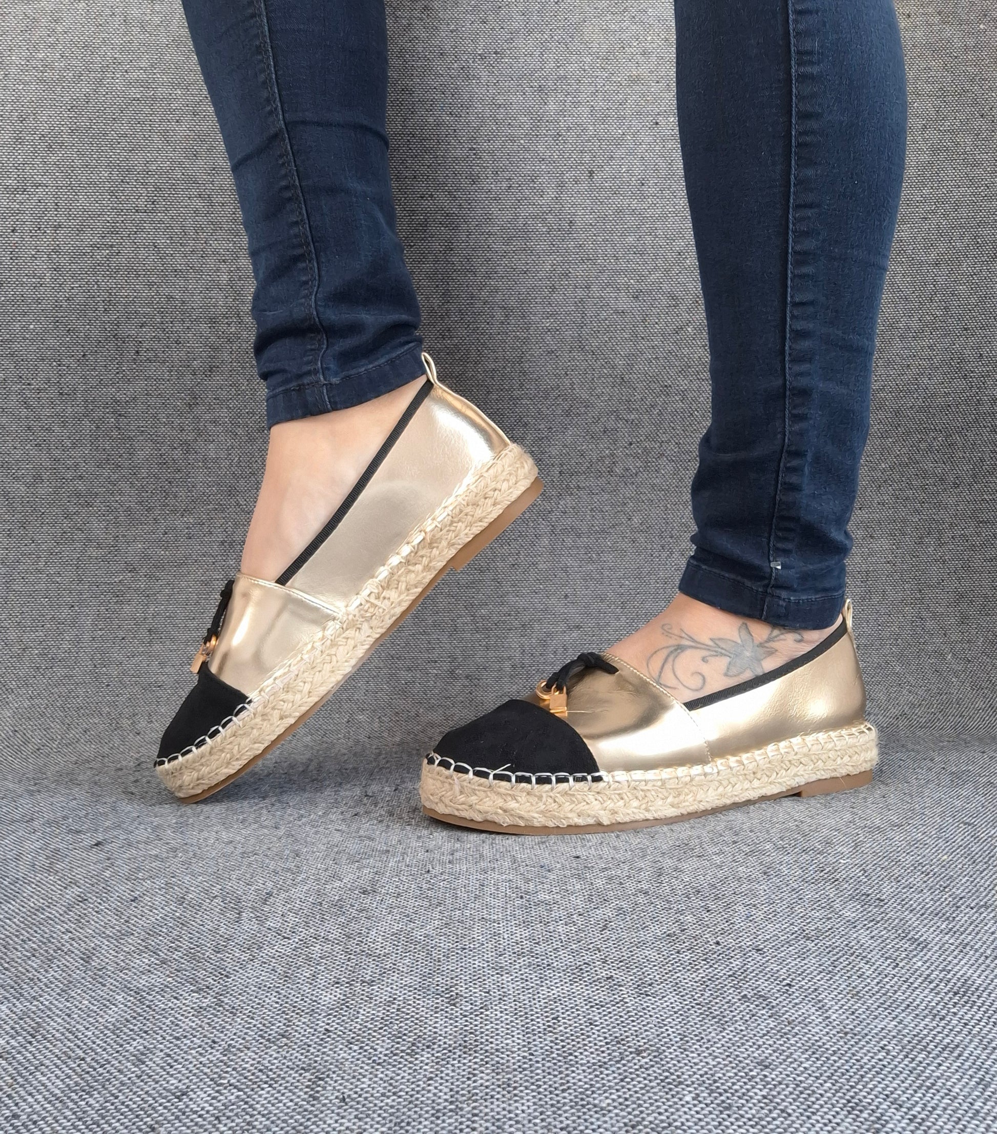 Espadrilles plates bicolore or et noir portées avec un jean, semelle tressée en jute, bout noir et dessus doré