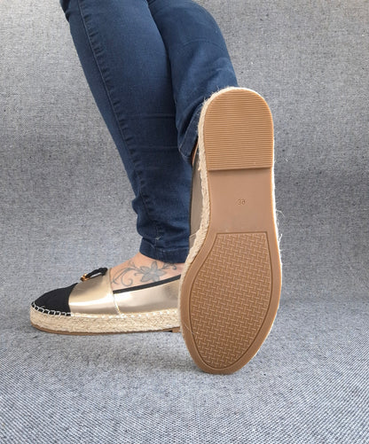 Semelle d'espadrilles plates bicolore or/noir avec tresse de jute, portées avec un jean bleu