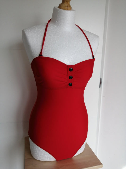 Red one-piece swimsuit with removable straps and buttons, displayed on white mannequin