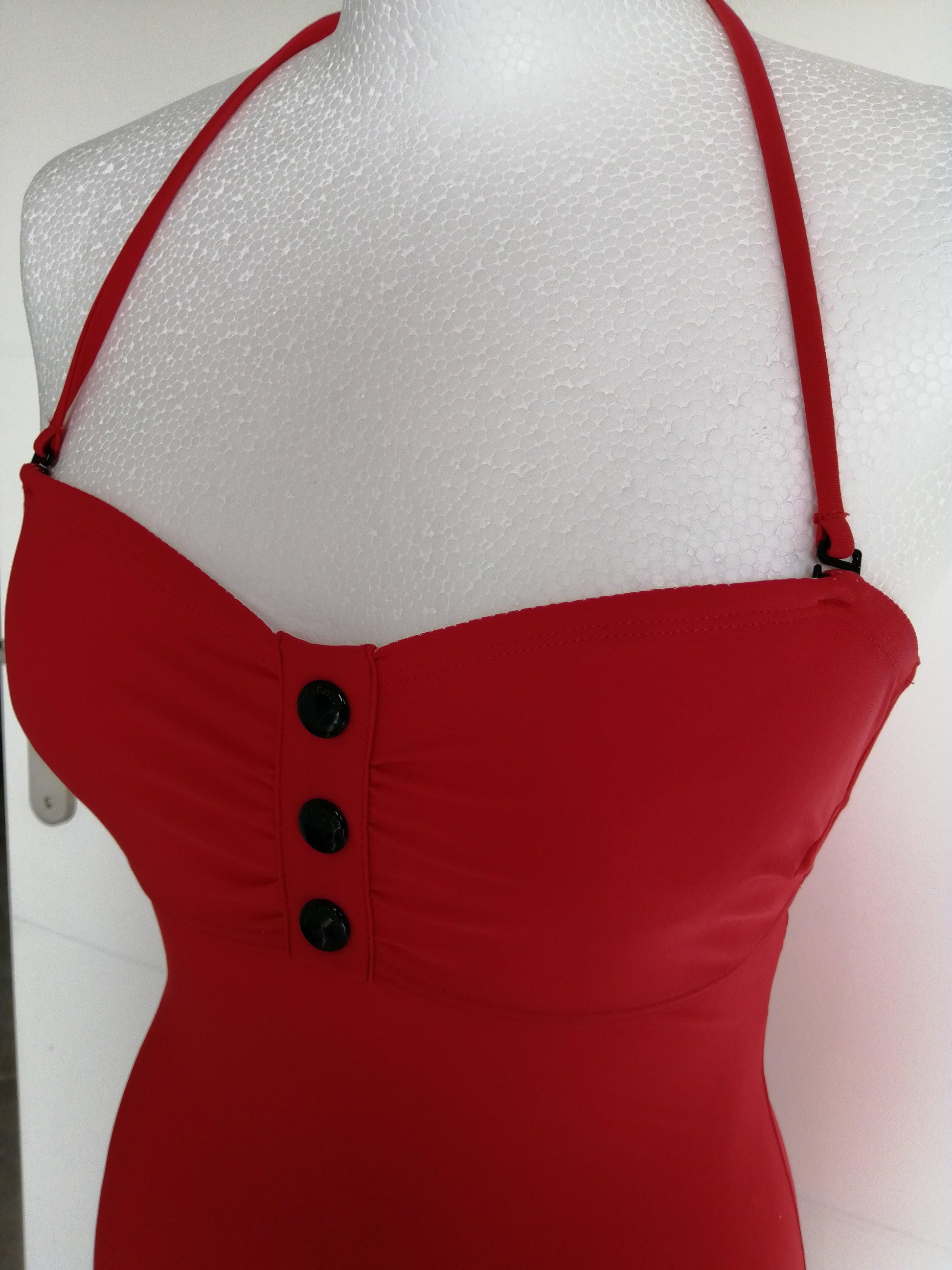 Red one-piece swimsuit with removable straps and three buttons, displayed on a mannequin