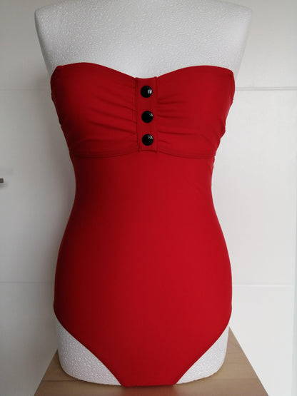 Red one-piece swimsuit with bustier top and black buttons, displayed on mannequin