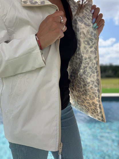 Manteau parka réversible blanc et léopard argenté Escandelle, doublure imprimée visible, porté ouvert près d'une piscine