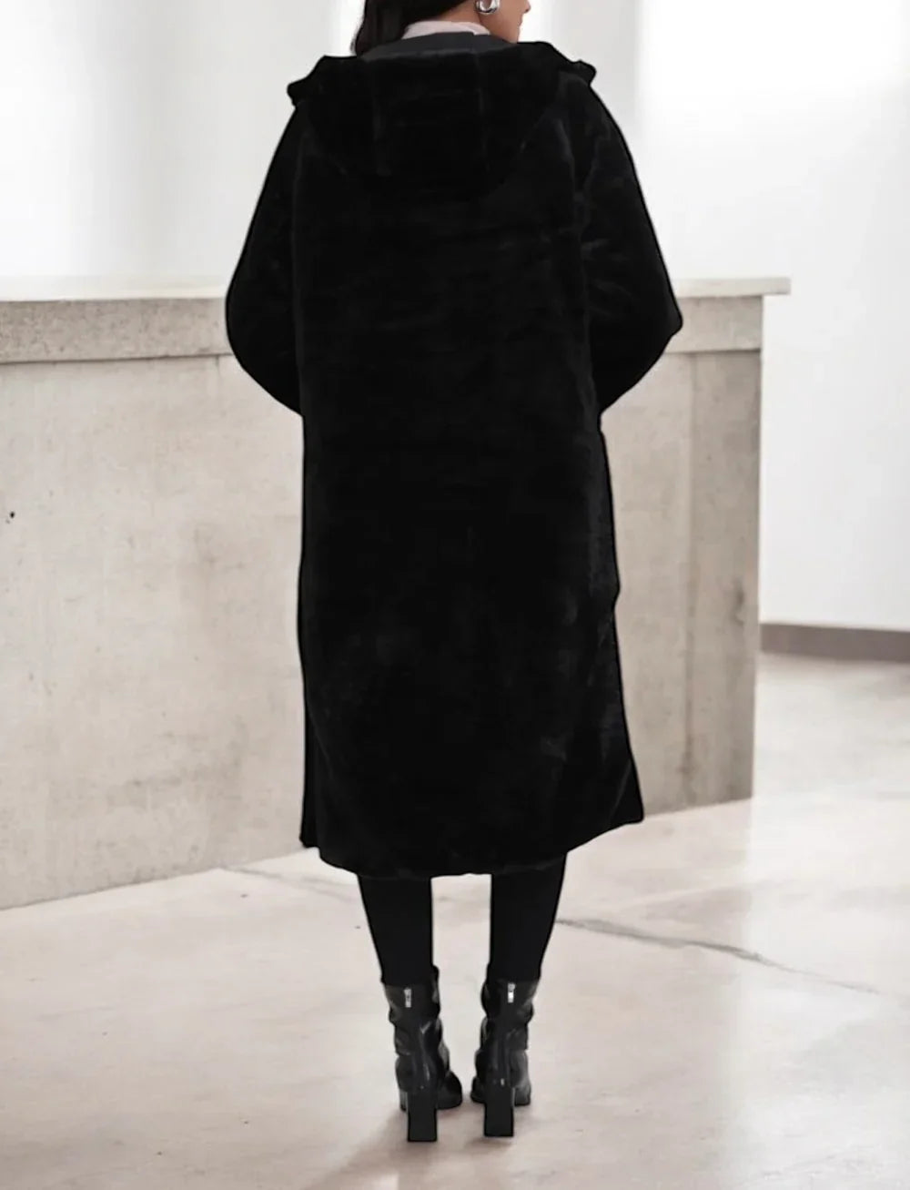 Manteau long réversible noir en fausse fourrure avec capuche et coupe ajustée, de dos