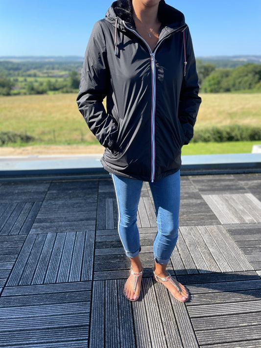 Woman wearing black Laura Jo mid-length raincoat with tricolor cord, outdoor setting