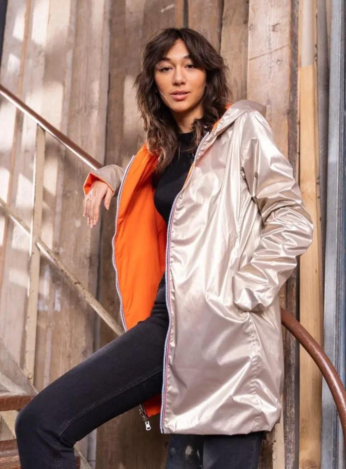 Woman wearing a reversible orange and gold Laura Jo raincoat from Le Petit Placard