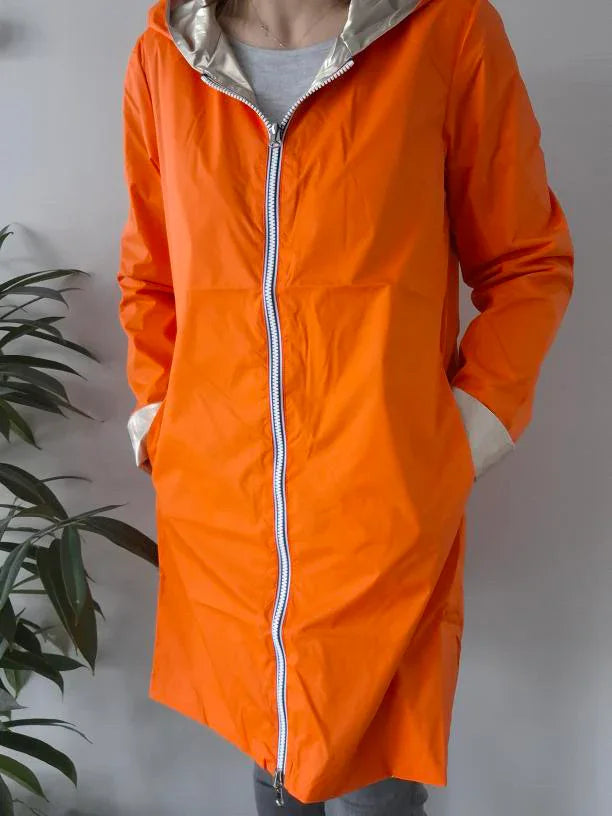 Woman wearing orange Laura Jo raincoat with hood, stylish waterproof jacket Le Petit Placard