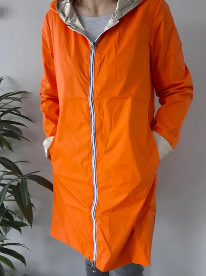 Woman wearing orange Laura Jo raincoat with hood, stylish waterproof jacket Le Petit Placard