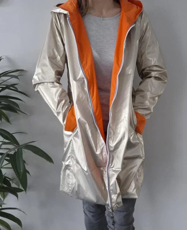 Woman wearing shiny beige Laura Jo raincoat with orange lining, trendy outerwear from Le Petit Placard